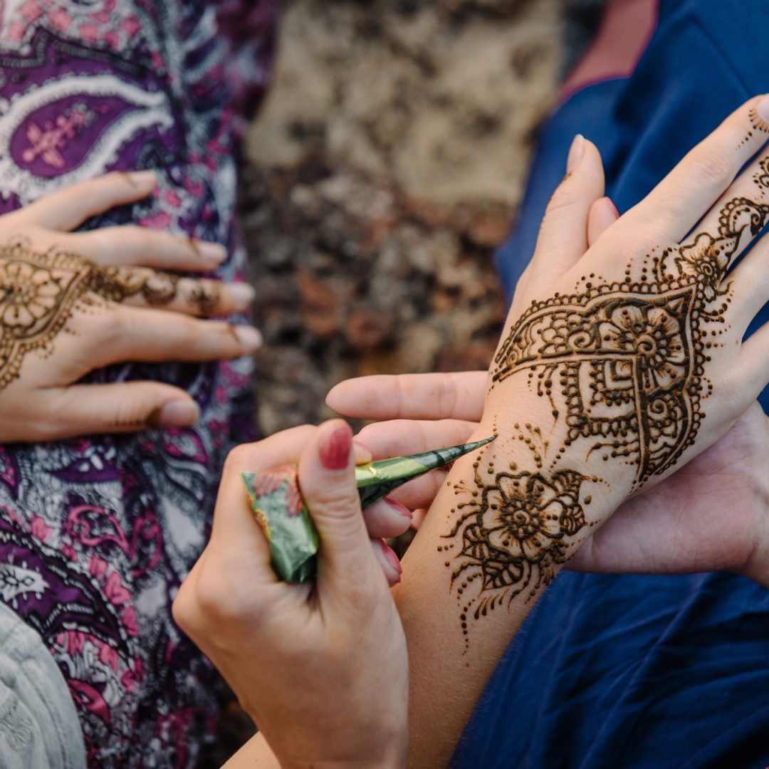 Applying henna tattoo on women hands. Mehndi is traditional Indian decorative art.