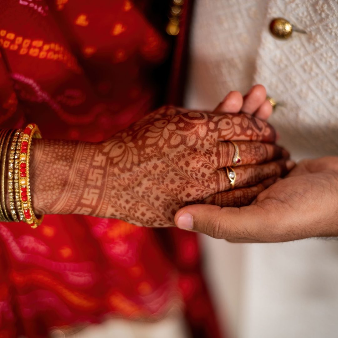 Closeup of Indian marriage couple hands with henna and jewelry