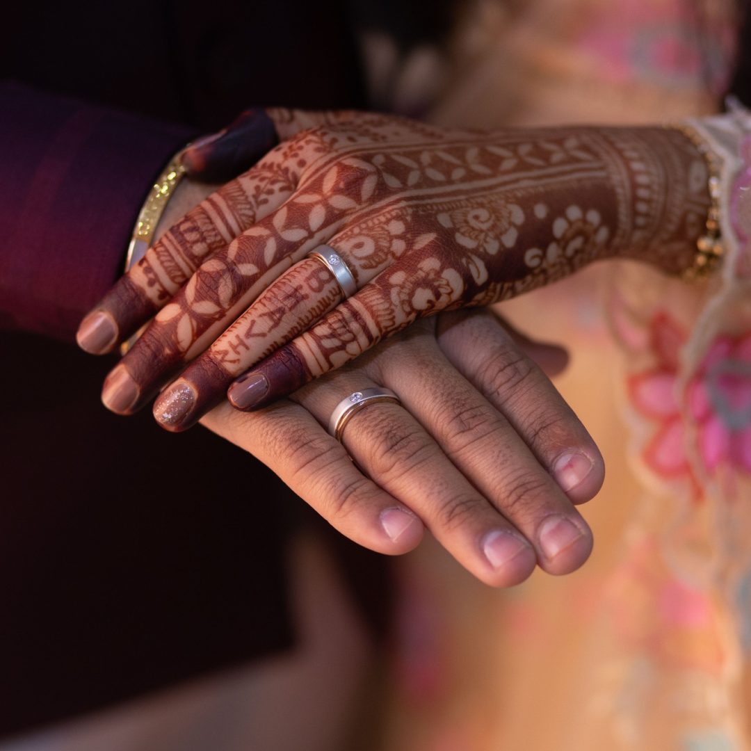 Happy wedding couple holding hands. The woman's hand with intricate henna.