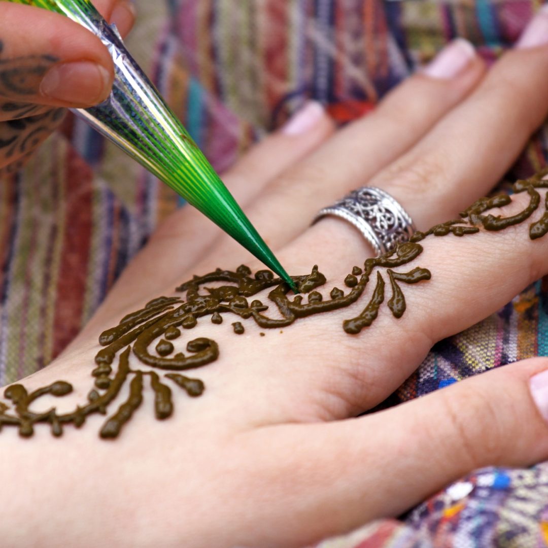 Human hand being decorated with henna tattoo