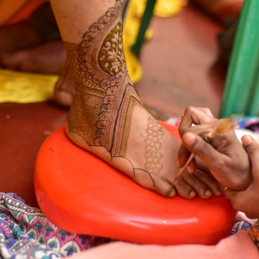 Woman applying henna on female foot